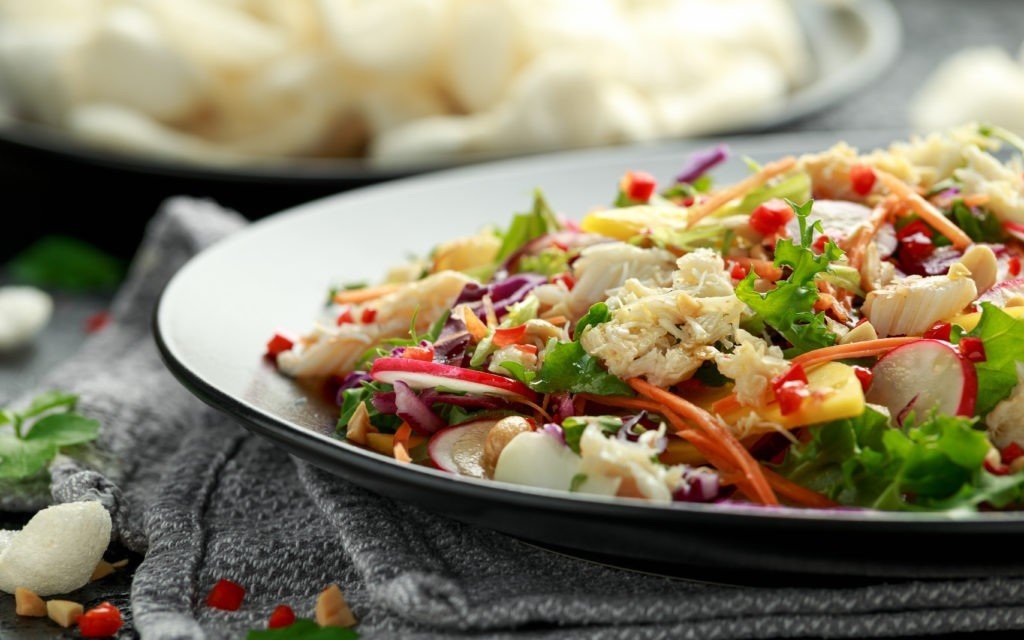 Crab salad with vegetables, radish, carrots, mango, pine nuts and prawn crackers